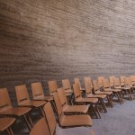 Two rows of arranged wooden chairs in an empty room