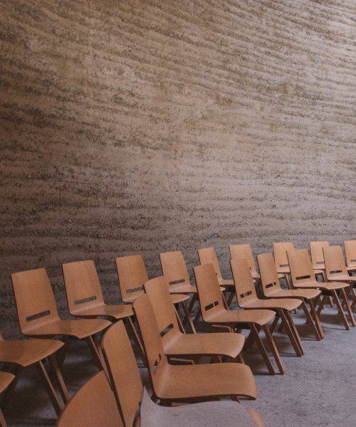 Two rows of arranged wooden chairs in an empty room