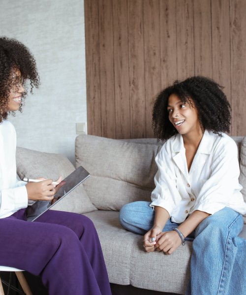 Two African women smile while talking during a counselling session